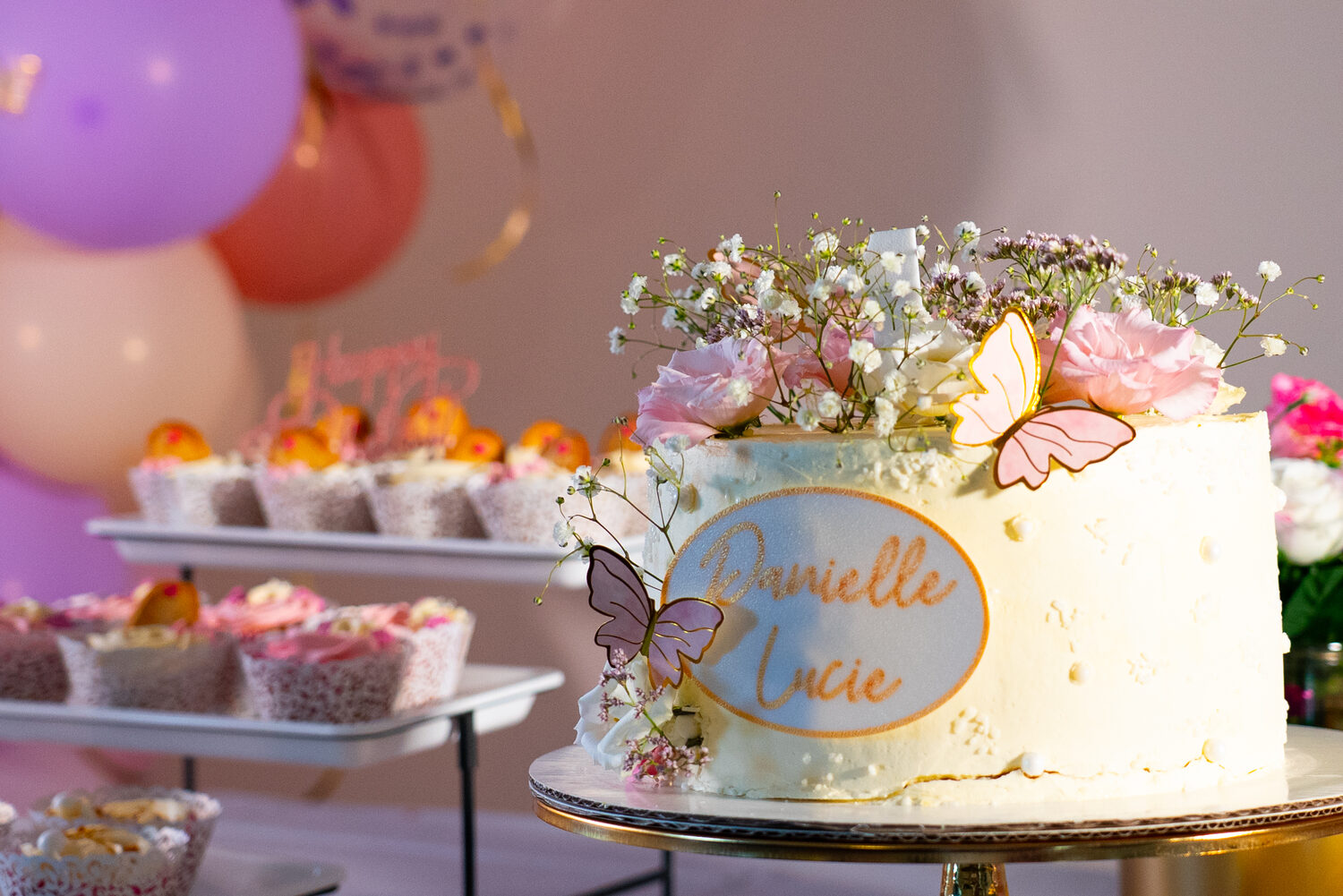 Gâteau d'anniversaire fleuri aux papillons, dressé sur présentoir doré