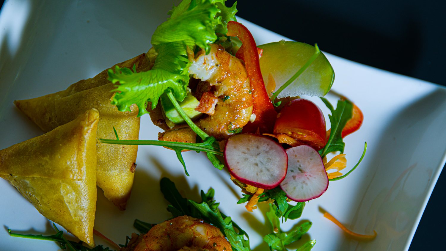 Samoussas croustillants et gambas marinées sur lit de roquette, radis et tomate